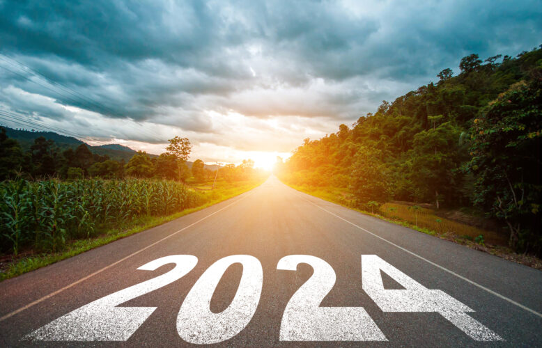 2024 is painted on asphalt road that leads to a distant sunrise.