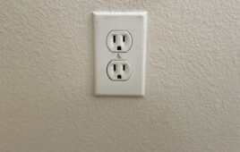 Slightly worn power outlet against an off-white wall.