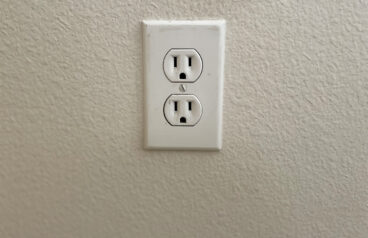 Slightly worn power outlet against an off-white wall.