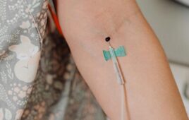 An IV line is shown going into the forearm of a patient.
