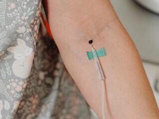 An IV line is shown going into the forearm of a patient.