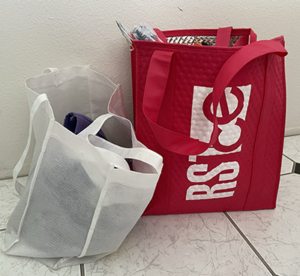 A red and a white tote bag sit on a tiled floor.